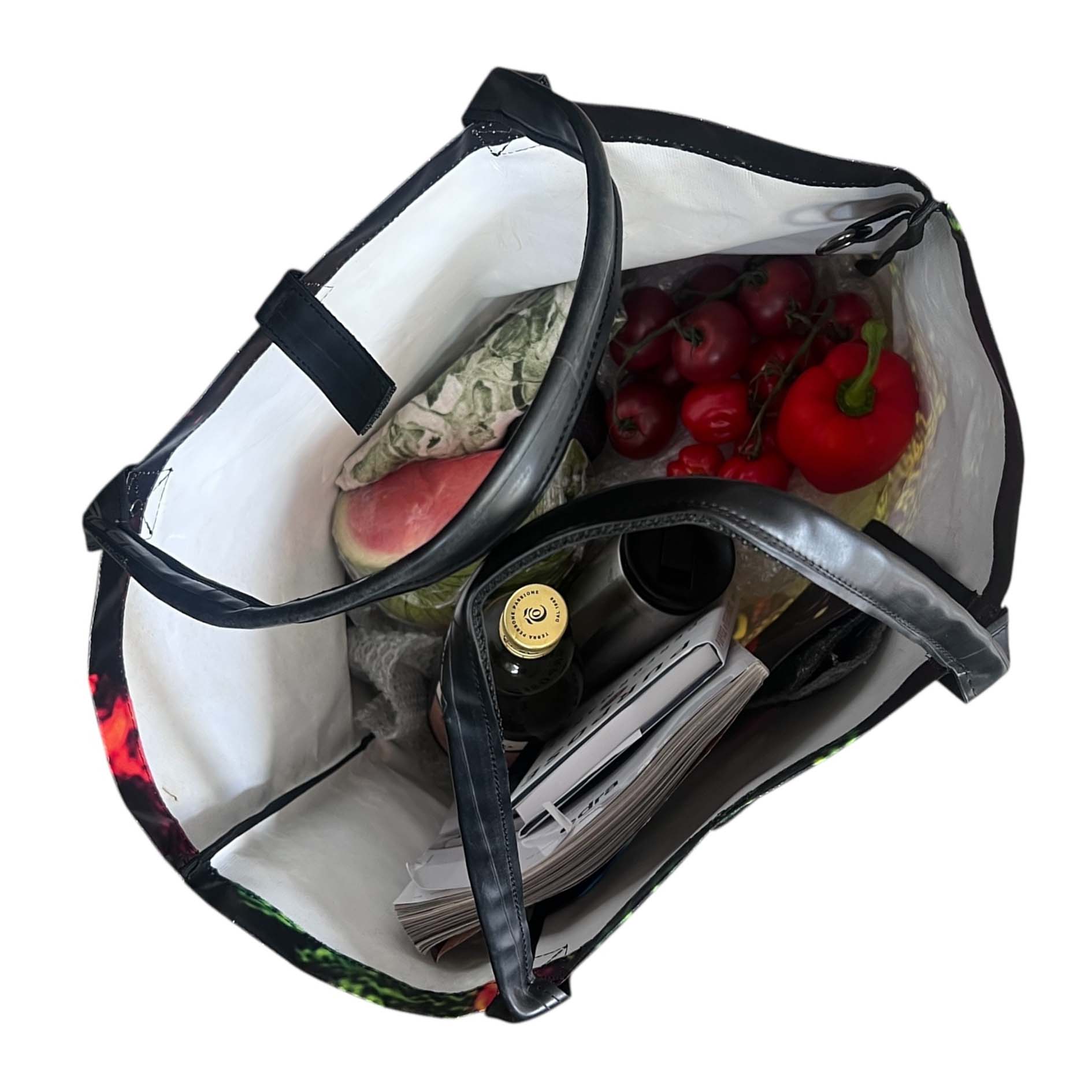Bag with food items including a bottle, fruits, and a newspaper.