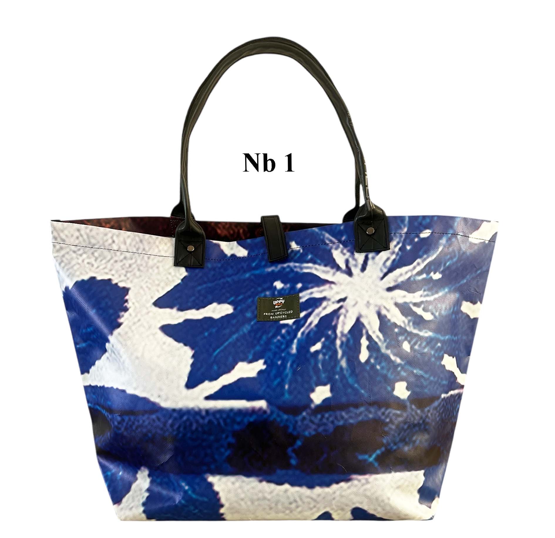 Blue and white patterned tote bag with black handles on a white background