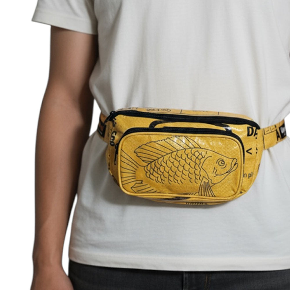 Person wearing a yellow fanny pack with fish design on a plain background